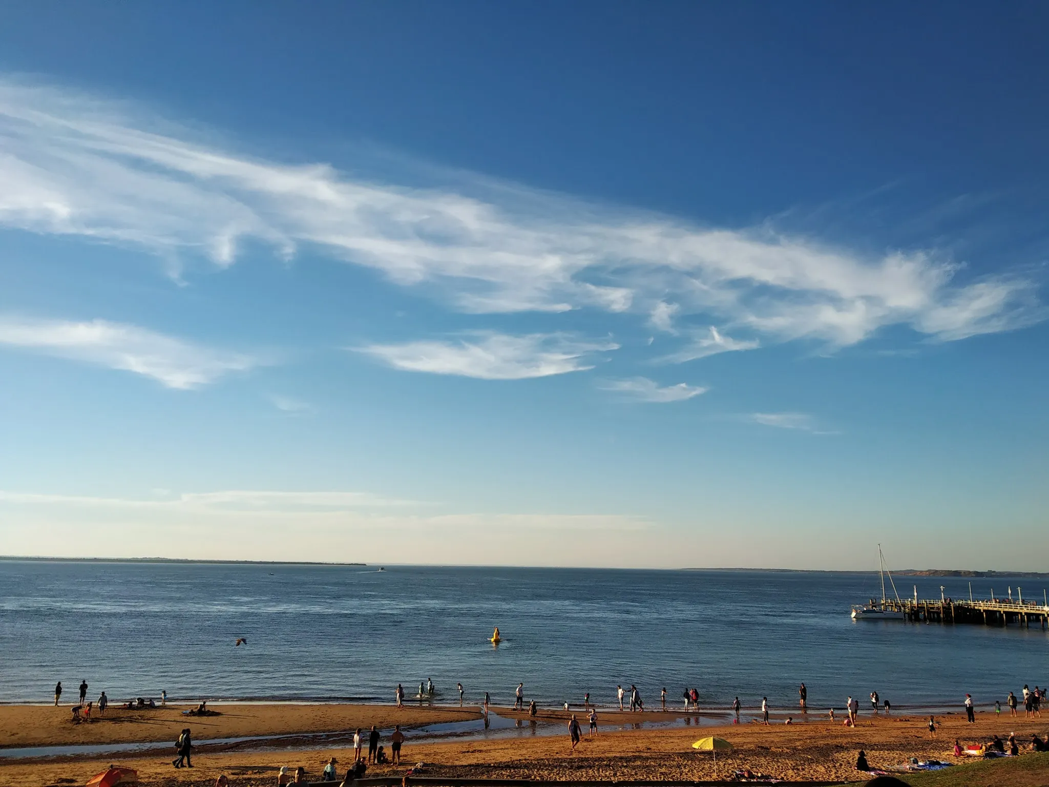 Wide panoramic view of Cowes beach Phillip Island on a sunny day with pier and people on the sand